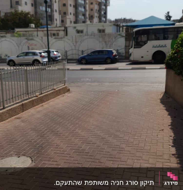 גדר מתכת לצד מדרכה מרוצפת בלבנים אדומות